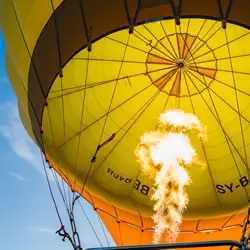 Low-angle view of a yellow hot air balloon with flame burst